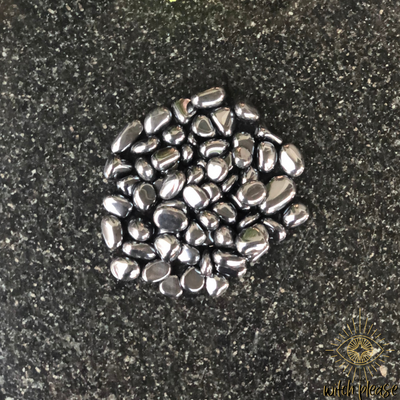 Tumbled hematite stones on a marble table.