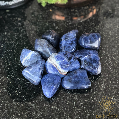 Tumbled sodalite stones on a black marble table